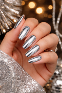 New Year's Eve nails in Airdrie, long silver chrome gel manicure in coffin shape, hand in sparkly sequin sleeve with festive bokeh lights at Top Nails 3