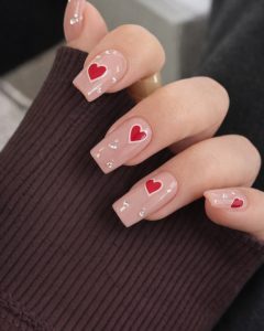 Valentine Nails long coffin set with nude base, red glitter tips, heart accents, glossy finish, Top Nails 3