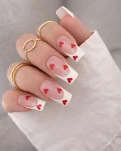 Valentine Nails sheer nude base with tiny red heart accents, short almond shape, glossy finish, Top Nails 3