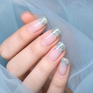 Sheer nude nails with blue floral glitter accents and abstract tips Floral Nails 2026 at Top Nails 3 Airdrie